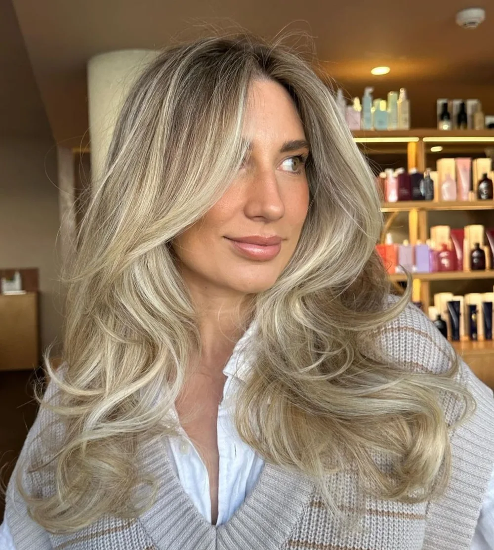 Butterfly cut long avec vagues souples et balayage blond sur couches encadrantes