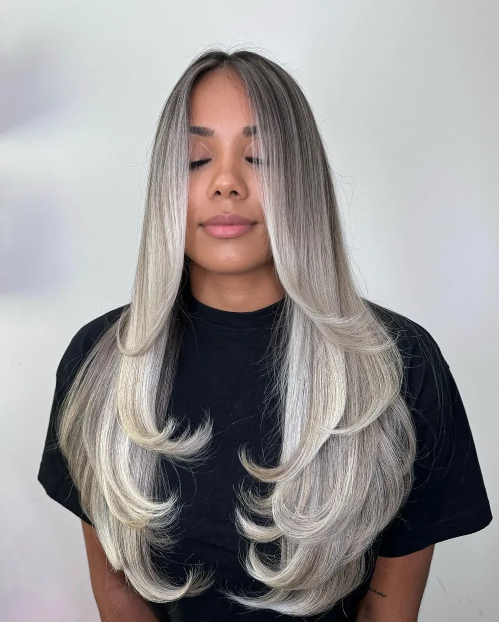 Butterfly cut sur cheveux longs platine avec pointes flippées et couches nettes
