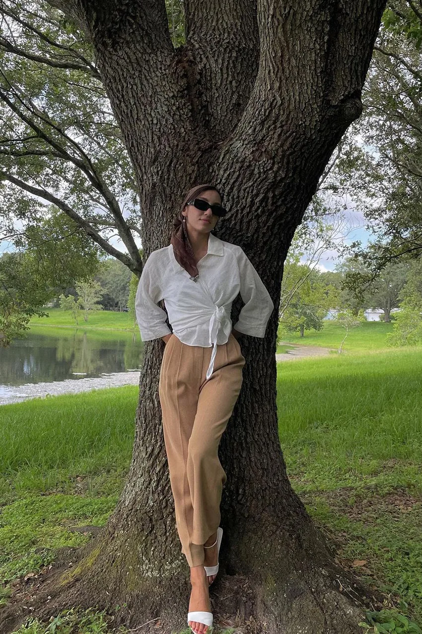 Chemisier blanc noué porté avec un pantalon camel et des mules