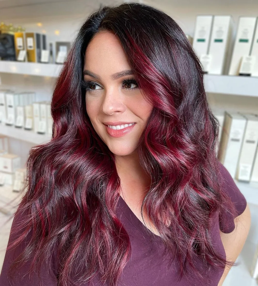 Cheveux bordeaux prune profond avec reflets sur peau claire, longues vagues