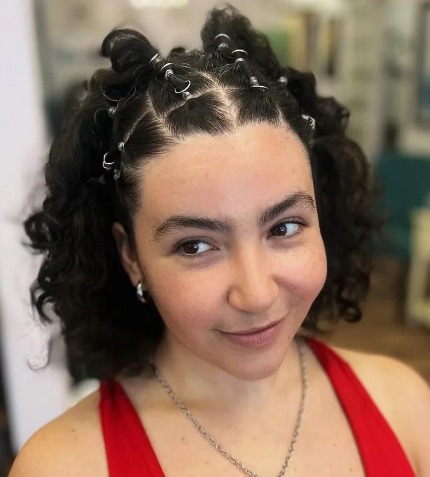 Cheveux bouclés années 2000 avec demi-tresses, raies carrées et piercing capillaire