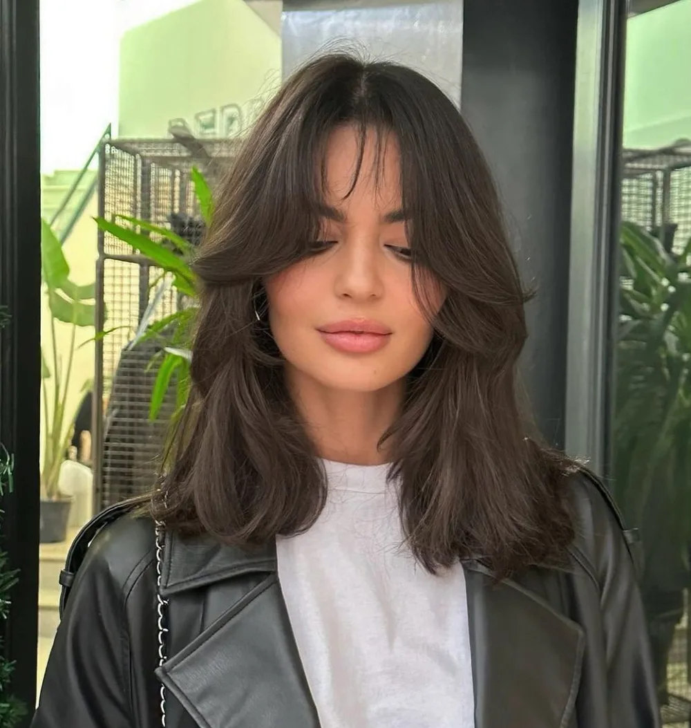 Cheveux brun foncé mi-longs avec mèches encadrantes et frange rideau pour visage carré