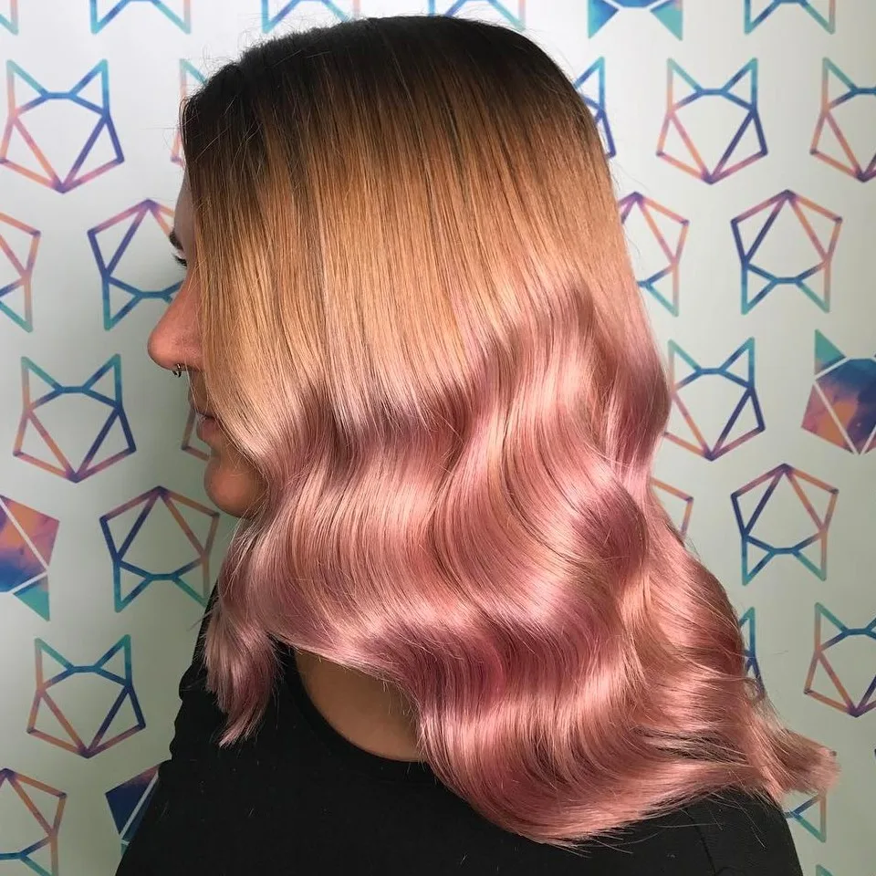 Cheveux en dégradé rose gold métallisé avec brillance sur ondulations