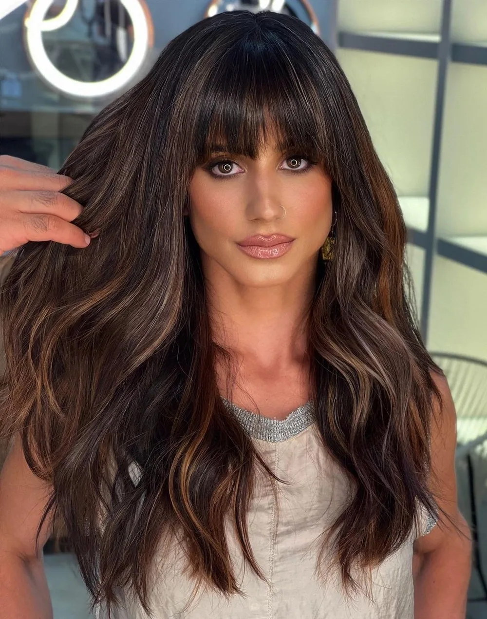 Cheveux longs ondulés brun foncé avec frange fournie et reflets caramel pour visage carré