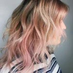 Cheveux rose gold en dégradé sur peau claire, longueurs ondulées