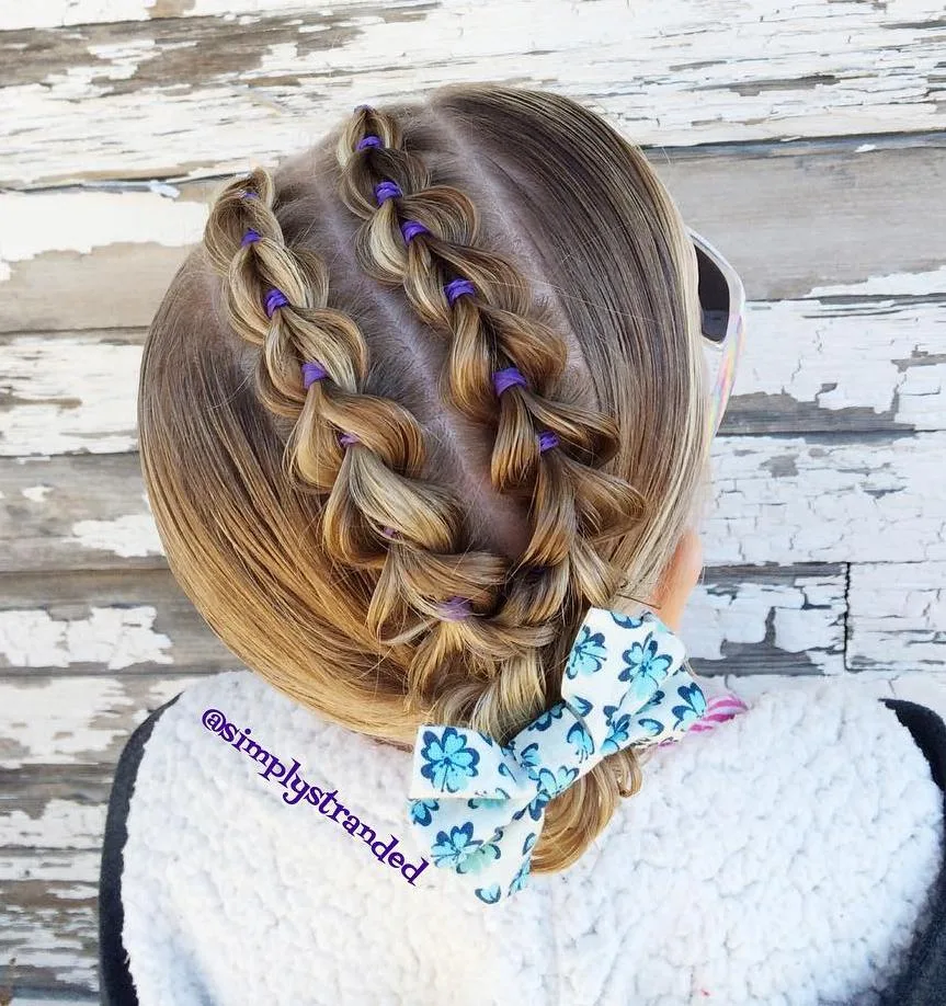 Chignon petite fille avec tresses pull-through disposées en diagonale et nœud