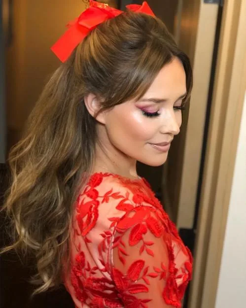 Coiffure avec nœud rouge vif posé sur cheveux ondulés châtains