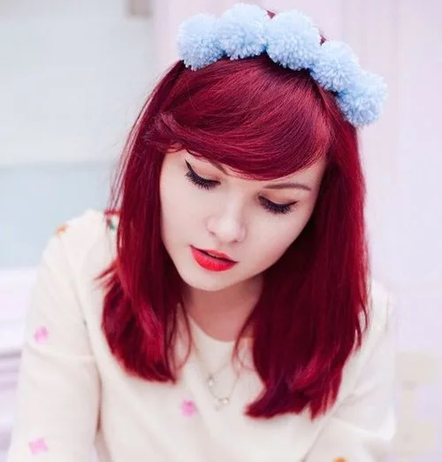 Coiffure avec serre-tête à pompons blancs sur cheveux rouges et frange