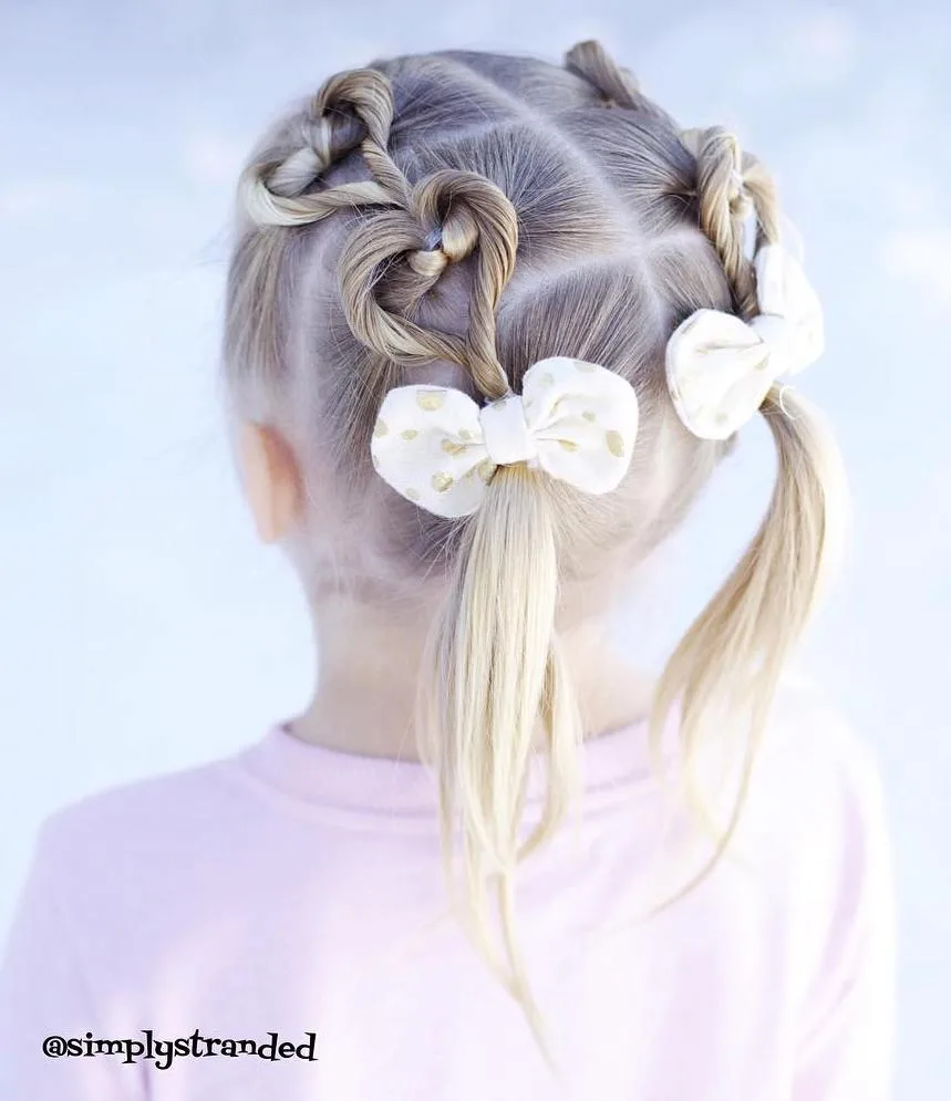 Coiffure petite fille avec couettes ornées de doubles cœurs torsadés et nœuds