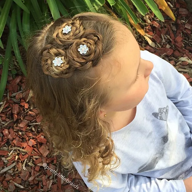 Coiffure petite fille en nid tressé décoré de petites fleurs blanches