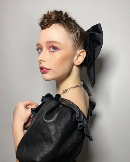 Coiffure relevée ornée d'un grand nœud noir en satin, look automne sophistiqué