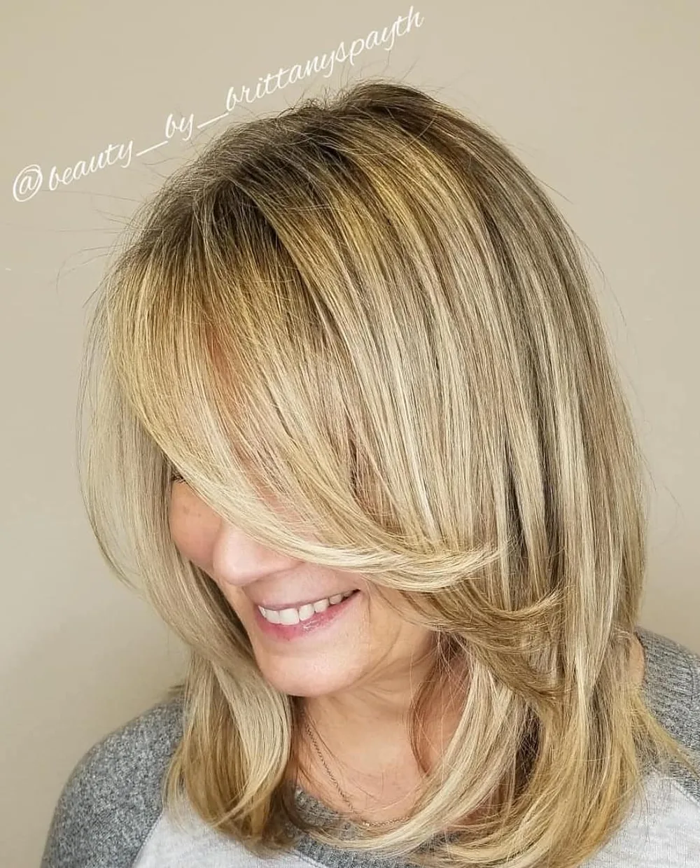 Coupe midi blonde avec longue frange plumeuse balayant le visage