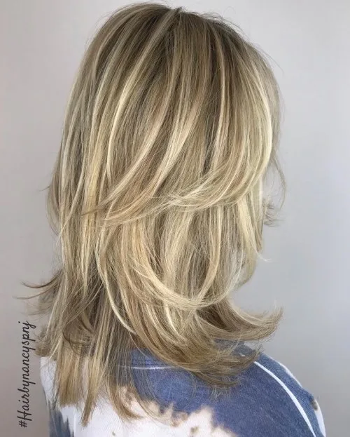 Coupe shag mi-longue allongée avec couches plumetées et balayage blond doré