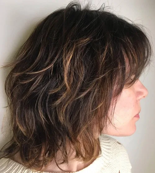 Coupe shag mi-longue brune décoiffée avec mèches caramel et frange effilée