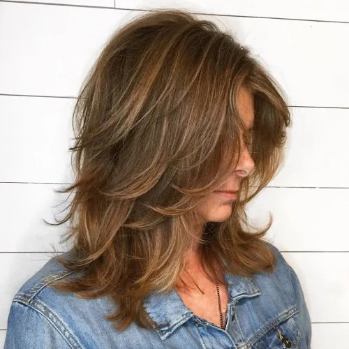 Coupe shag mi-longue effet plumeté avec frange peekaboo châtain doré
