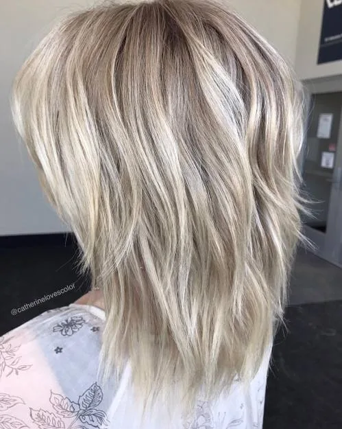 Coupe shullet texturée entre shag et mullet blond avec couches épaisses