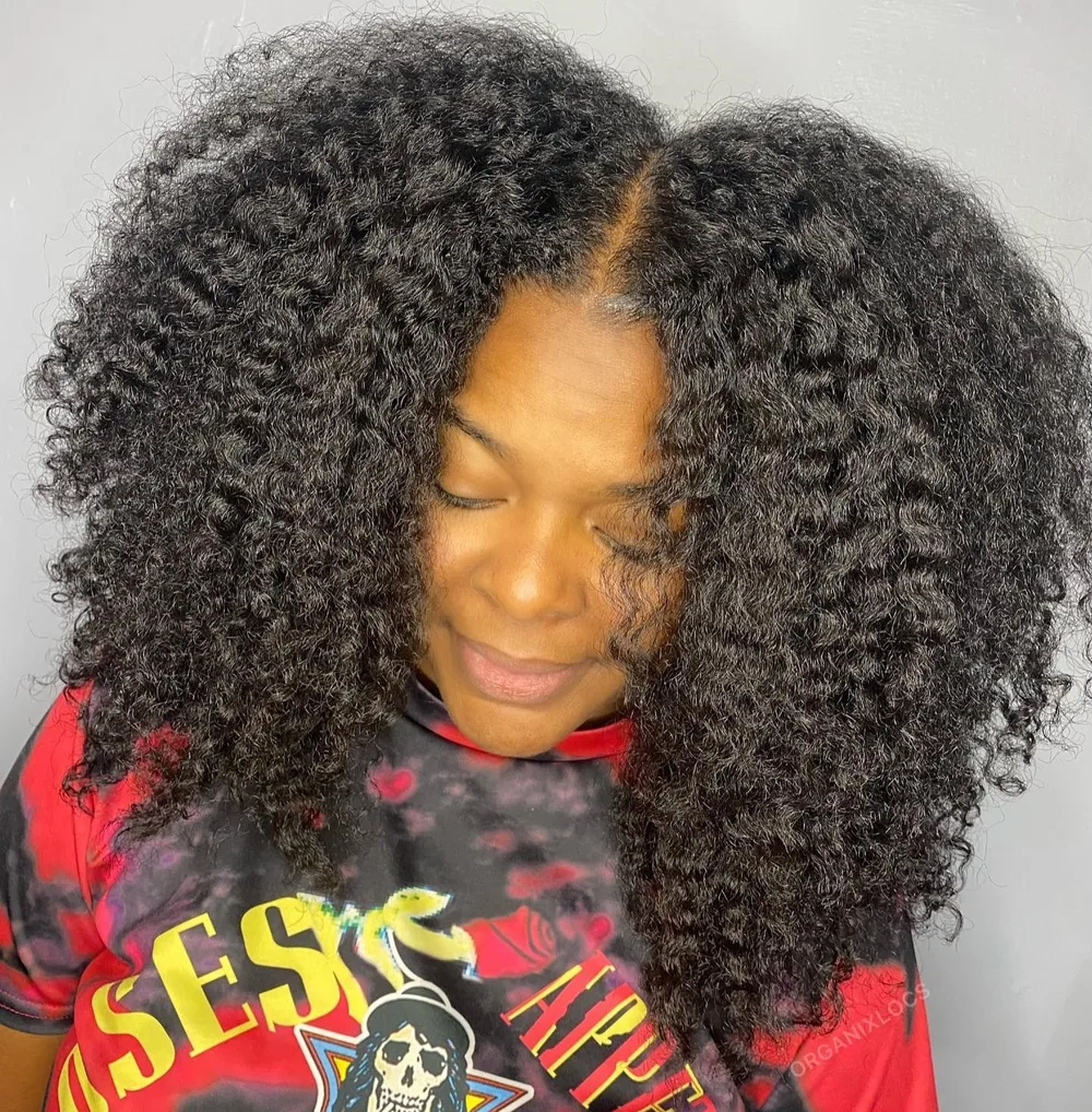 Crinière afro volumineuse à raie au milieu et boucles définies sur les côtés