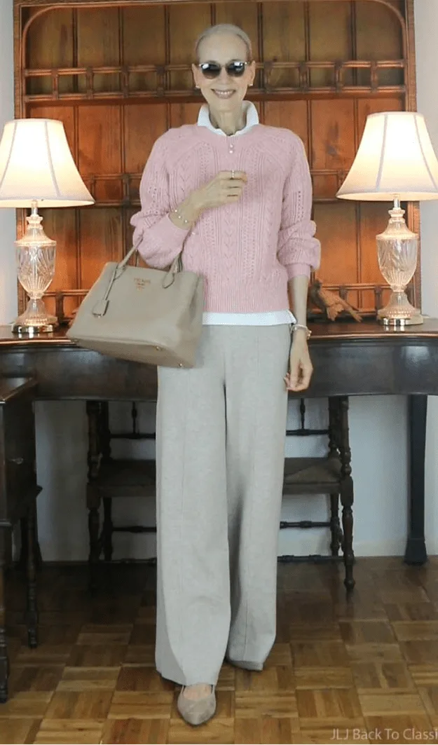 Femme de plus de 50 ans en pull rose tendance sur base neutre, style automne actuel