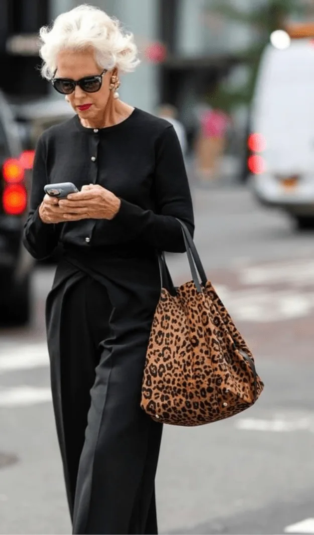 Femme de plus de 50 ans en total look noir avec sac léopard, bijoux adaptés à l'encolure