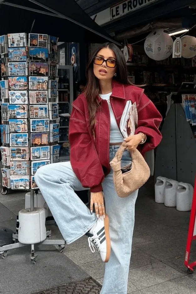 Femme en bomber bordeaux avec jean clair large et baskets dans la rue