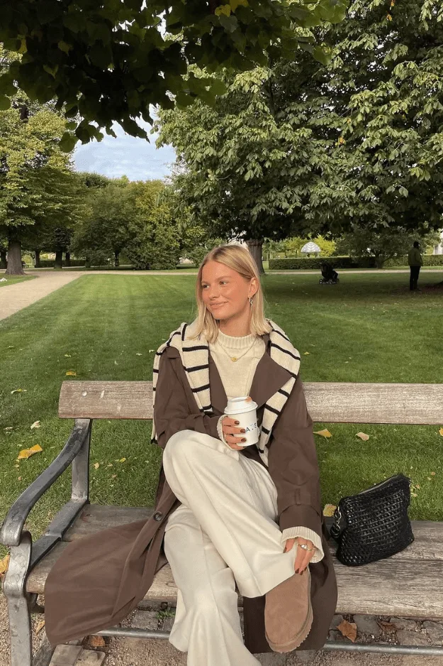 Femme en look monochrome beige, cardigan et maille ton sur ton sur un banc