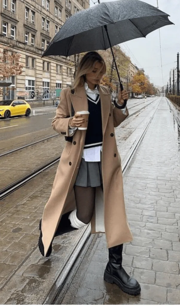 Femme en trench beige classique avec pull crème et bottines, look automne pluvieux