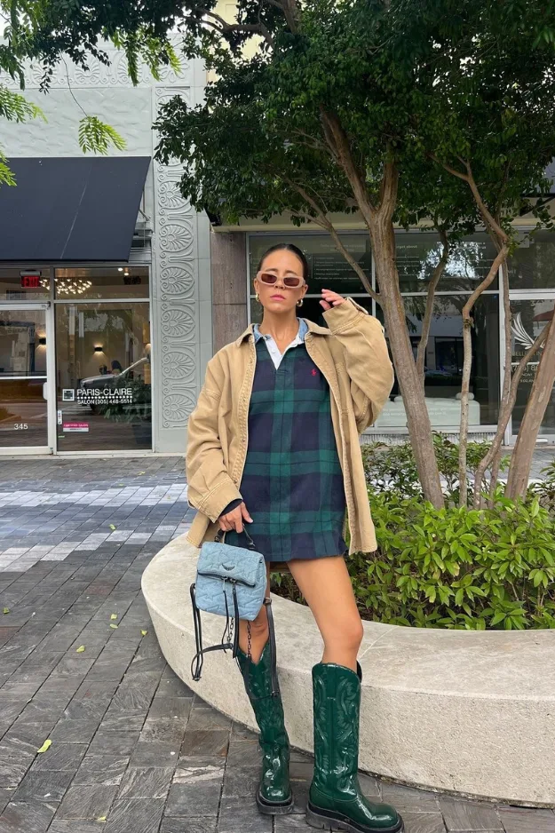Femme en veste beige légère portée sur une robe à carreaux verte et bottes