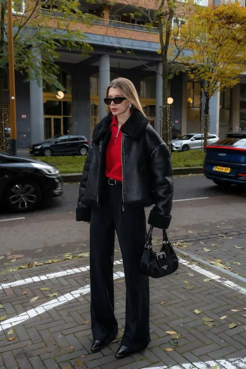 Femme en veste en cuir noire oversize avec haut rouge et pantalon noir
