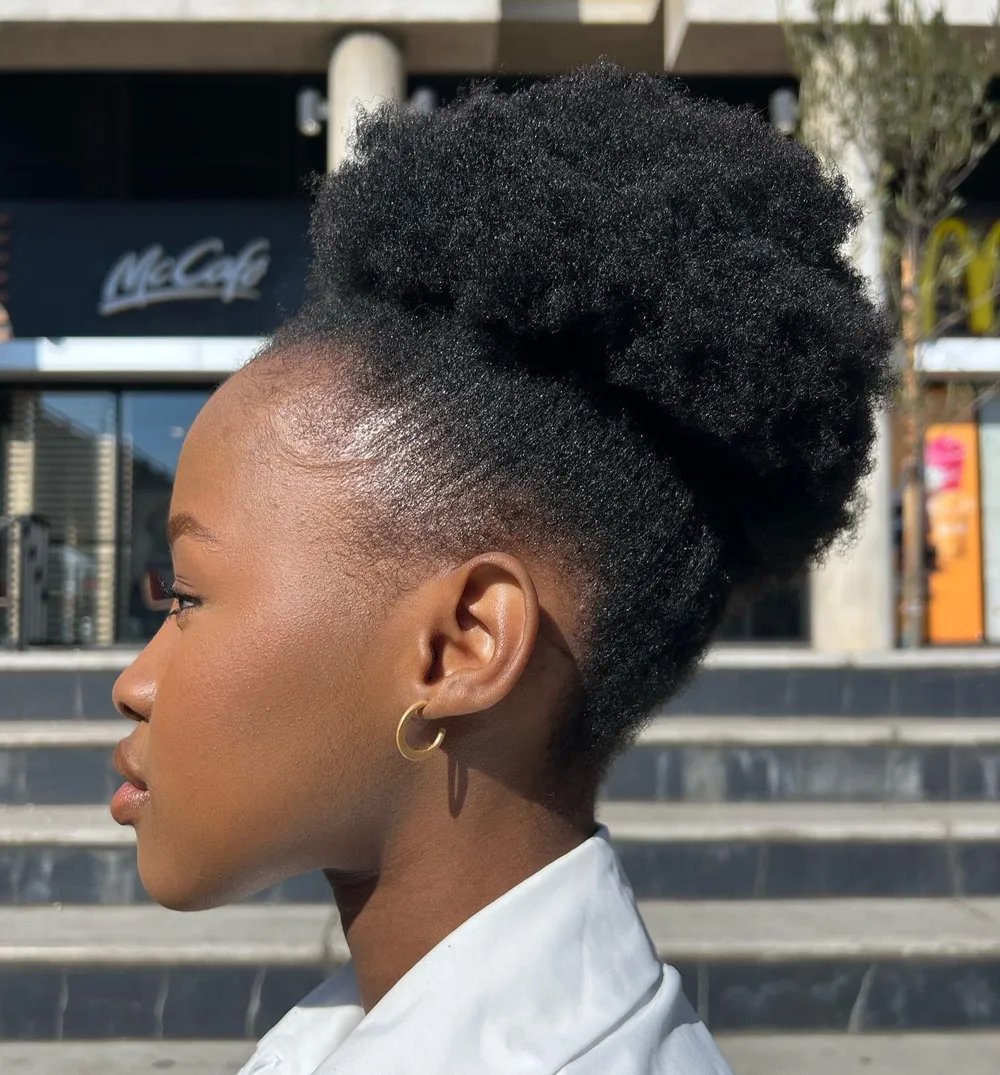 High puff afro volumineux rassemblé haut sur la tête, côtés dégagés