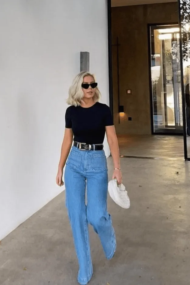 Jean large clair porté avec un tee noir ajusté et une ceinture large