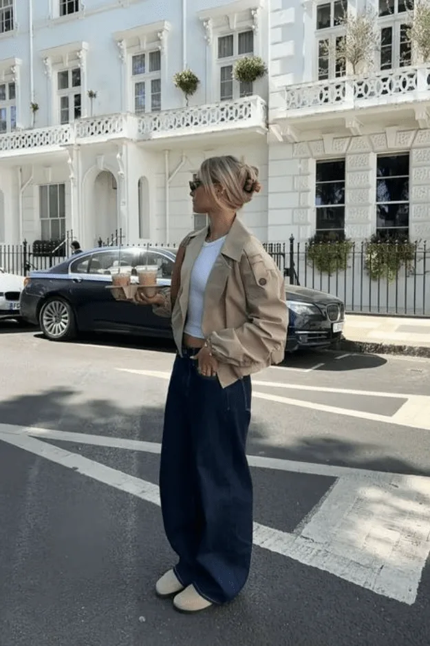 Jean large foncé porté avec un bomber beige court et des ballerines nude
