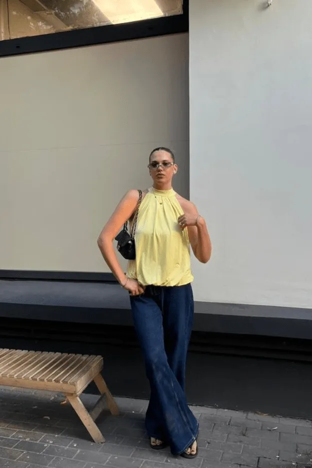 Jean large foncé porté avec un haut licou jaune fluide
