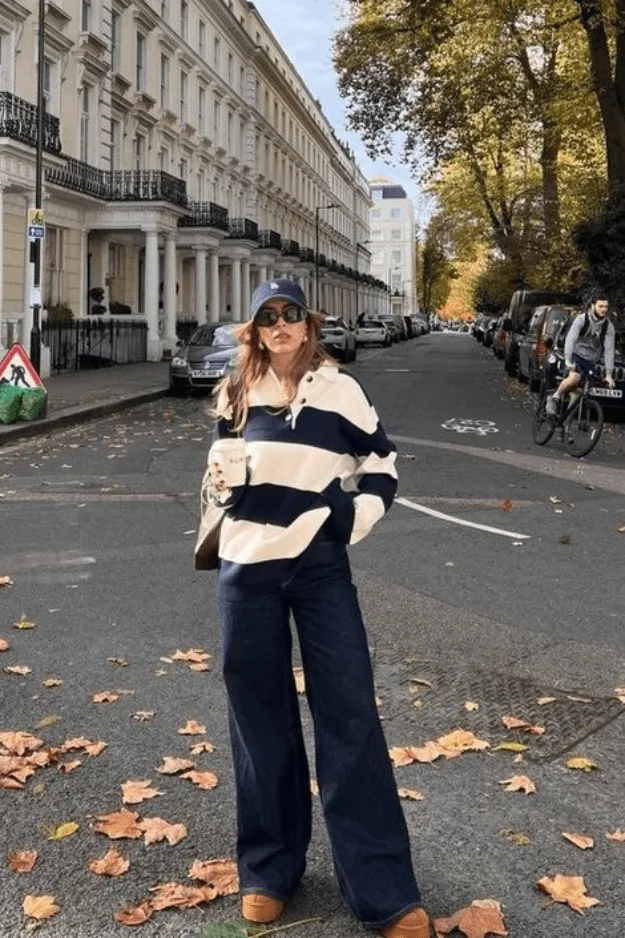 Jean large foncé porté avec un polo rugby rayé et des bottes UGG
