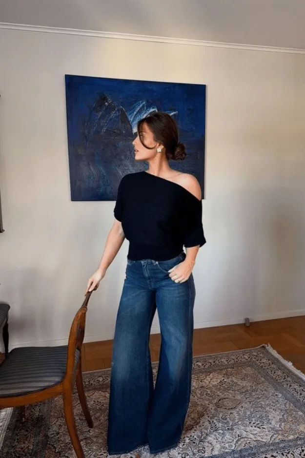 Jean large foncé porté avec une maille noire à épaule dénudée
