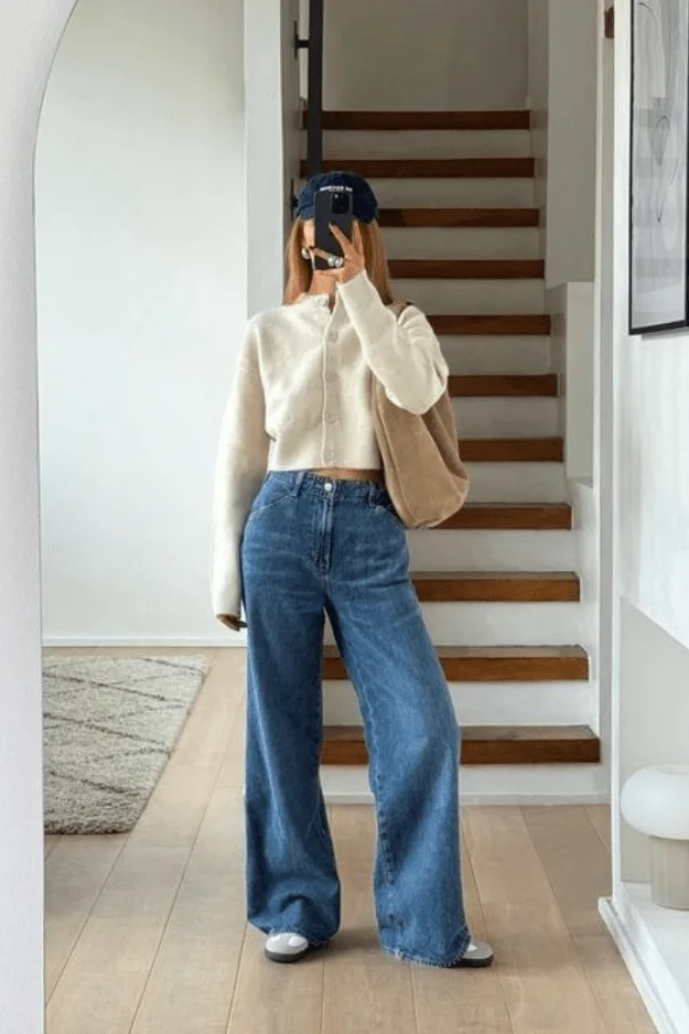 Jean large mi-clair porté avec un cardigan crème boutonné et une casquette