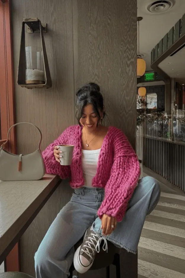 Jean large porté avec un cardigan rose vif en grosse maille et un top blanc