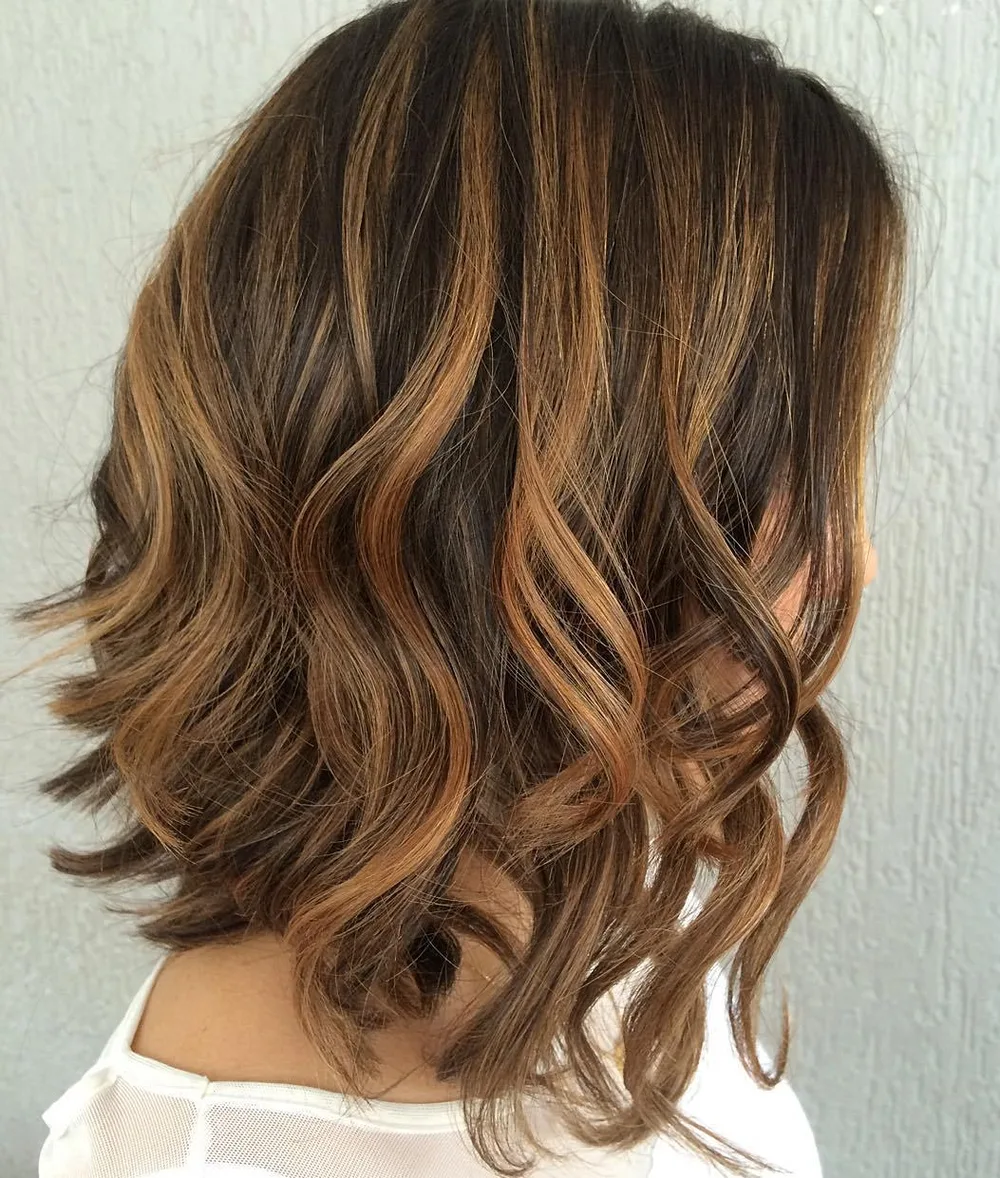 Lob dégradé brun foncé avec mèches tawny caramel sur boucles souples