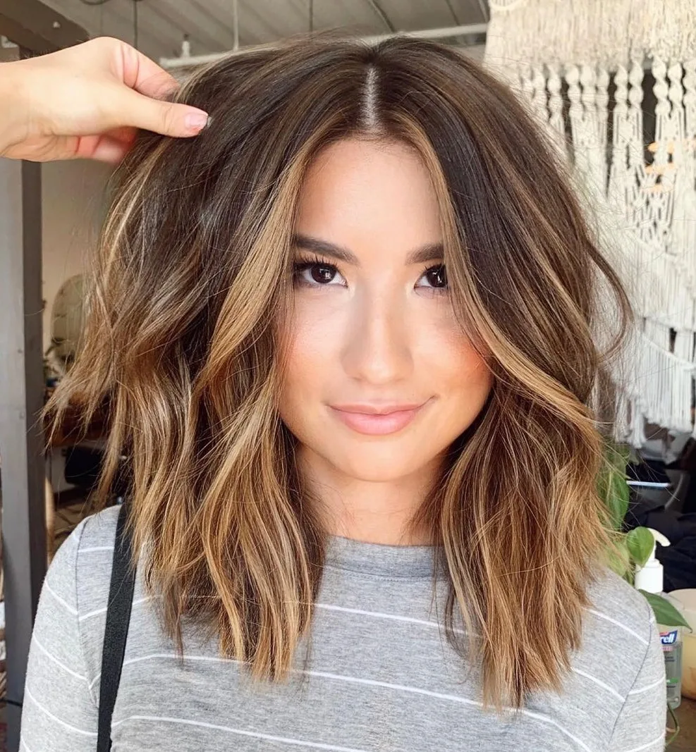 Lob ondulé plumeté aux pointes effilées et balayage adoucissant un visage carré