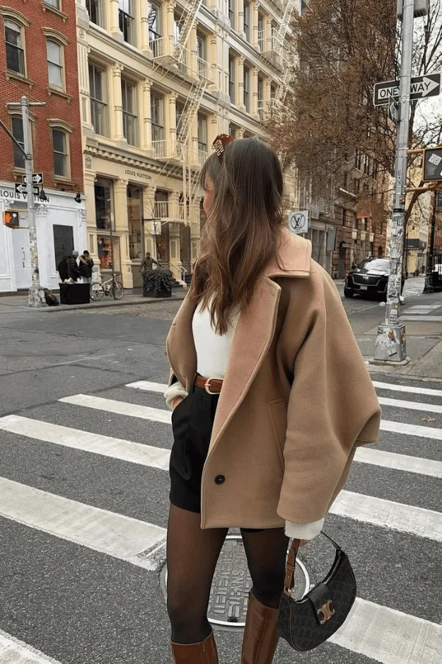 Look manteau camel oversize avec débardeur blanc, short noir, collants et bottes marron