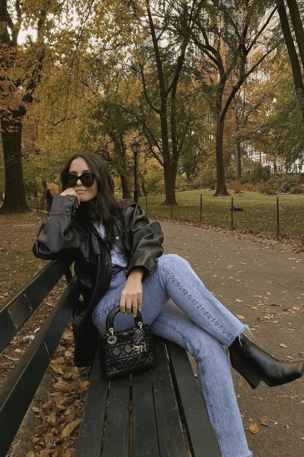 Look perfecto en cuir noir, jean clair et bottes plateforme noires sur un banc