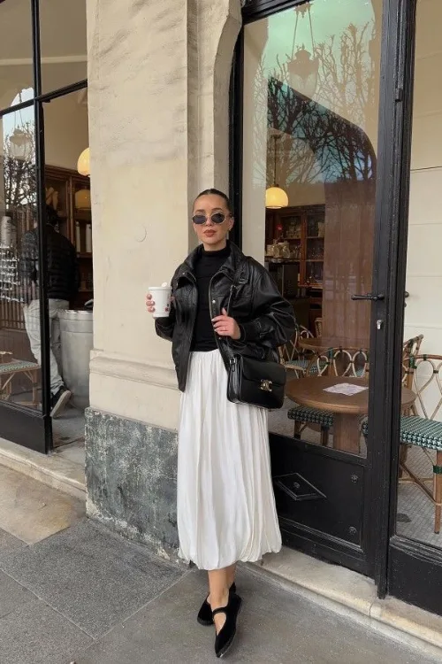 Look perfecto en cuir noir porté sur une jupe plissée blanche et escarpins