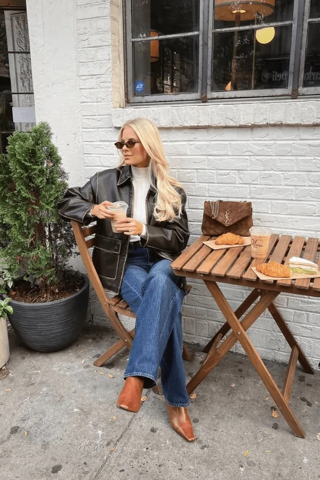 Look perfecto en cuir noir, tee-shirt crème, jean bleu, bottes et sac marron