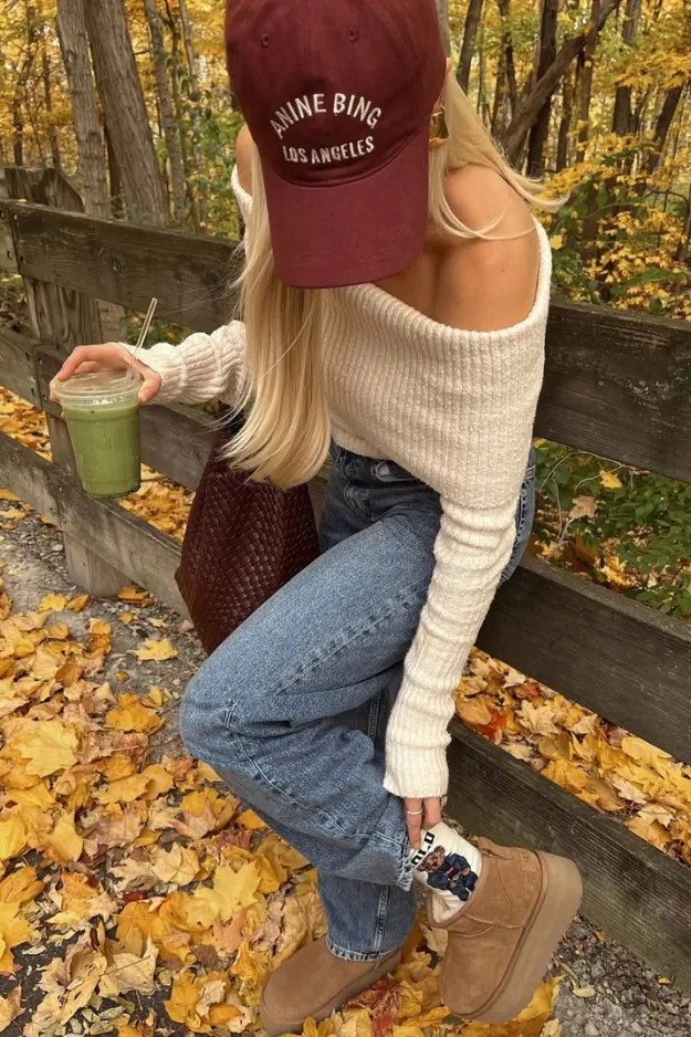 Look pull crème à épaule dénudée avec casquette rouge et jean, en extérieur