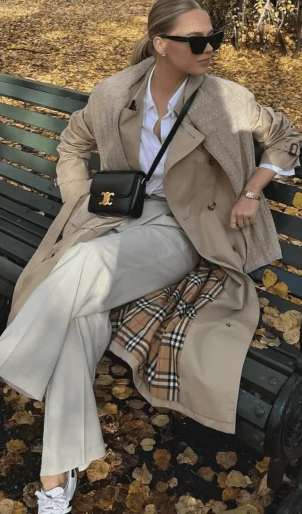 Look trench beige porté sur jupe à carreaux et bottes, feuilles d'automne
