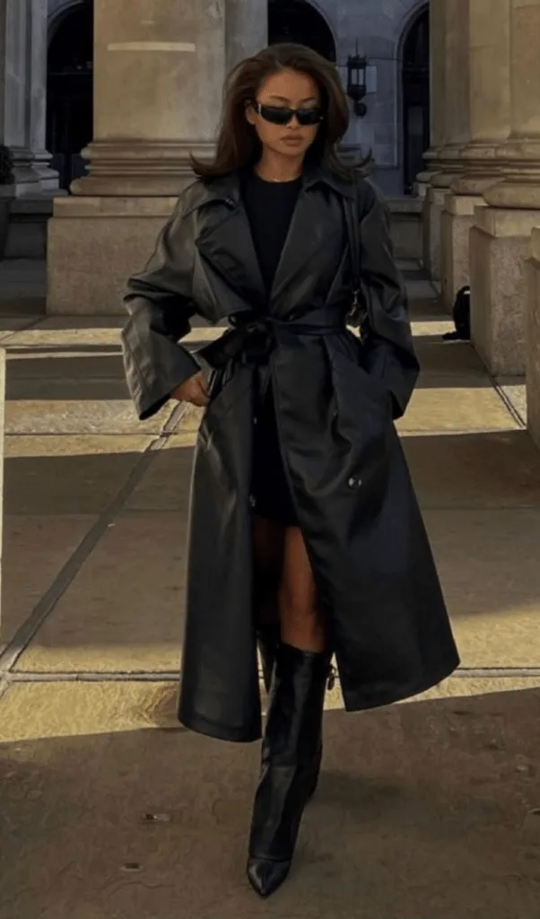 Look trench en cuir noir sur mini-robe avec bottes hautes, allure du soir