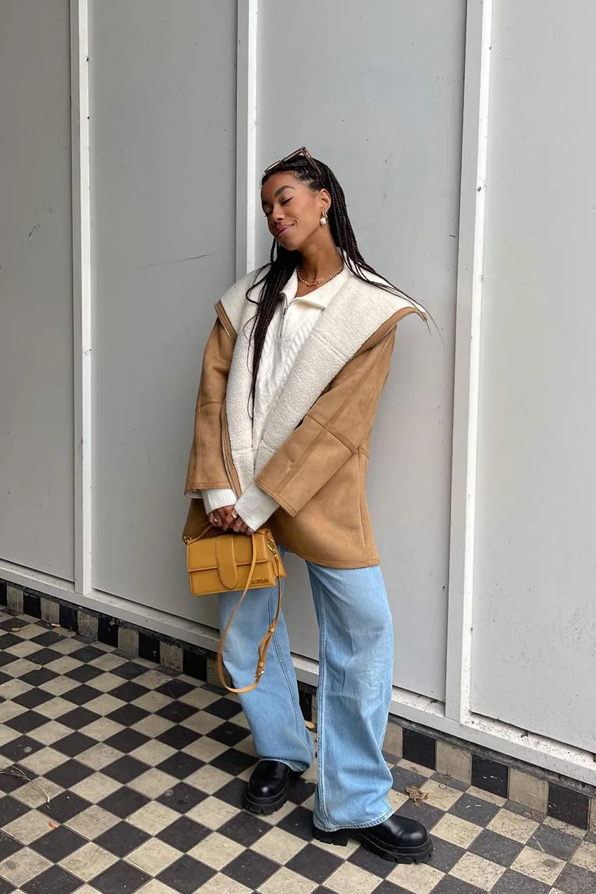 Manteau shearling camel porté avec un pull torsadé blanc et un jean