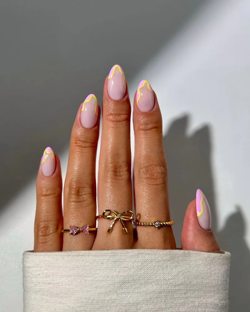 Manucure french base laiteuse avec vagues roses et contour jaune bubble sur ongles amande