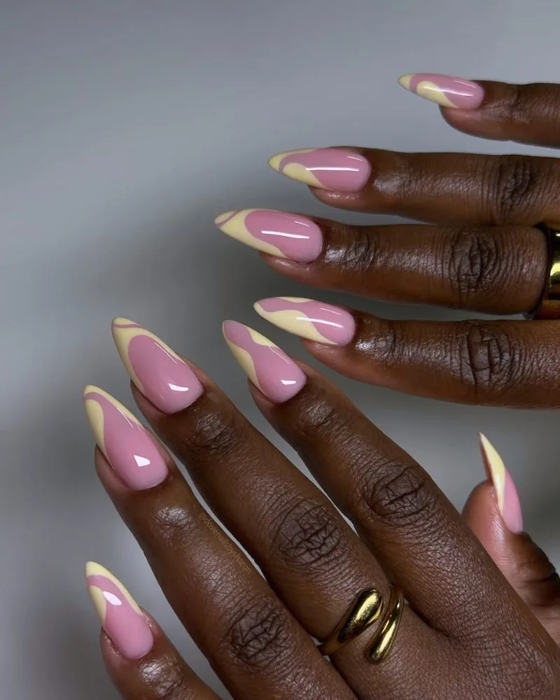 Manucure french base rose avec pointes jaune beurre en vague sur ongles amande