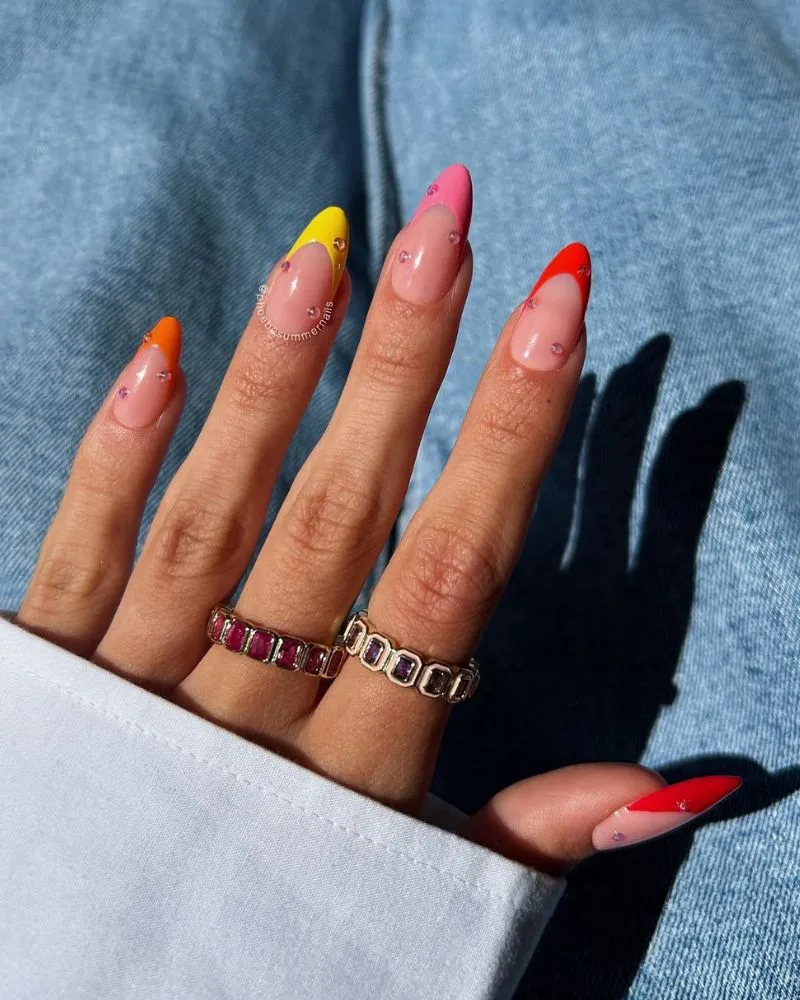 Manucure french néon multicolore aux teintes chaudes avec points strass roses