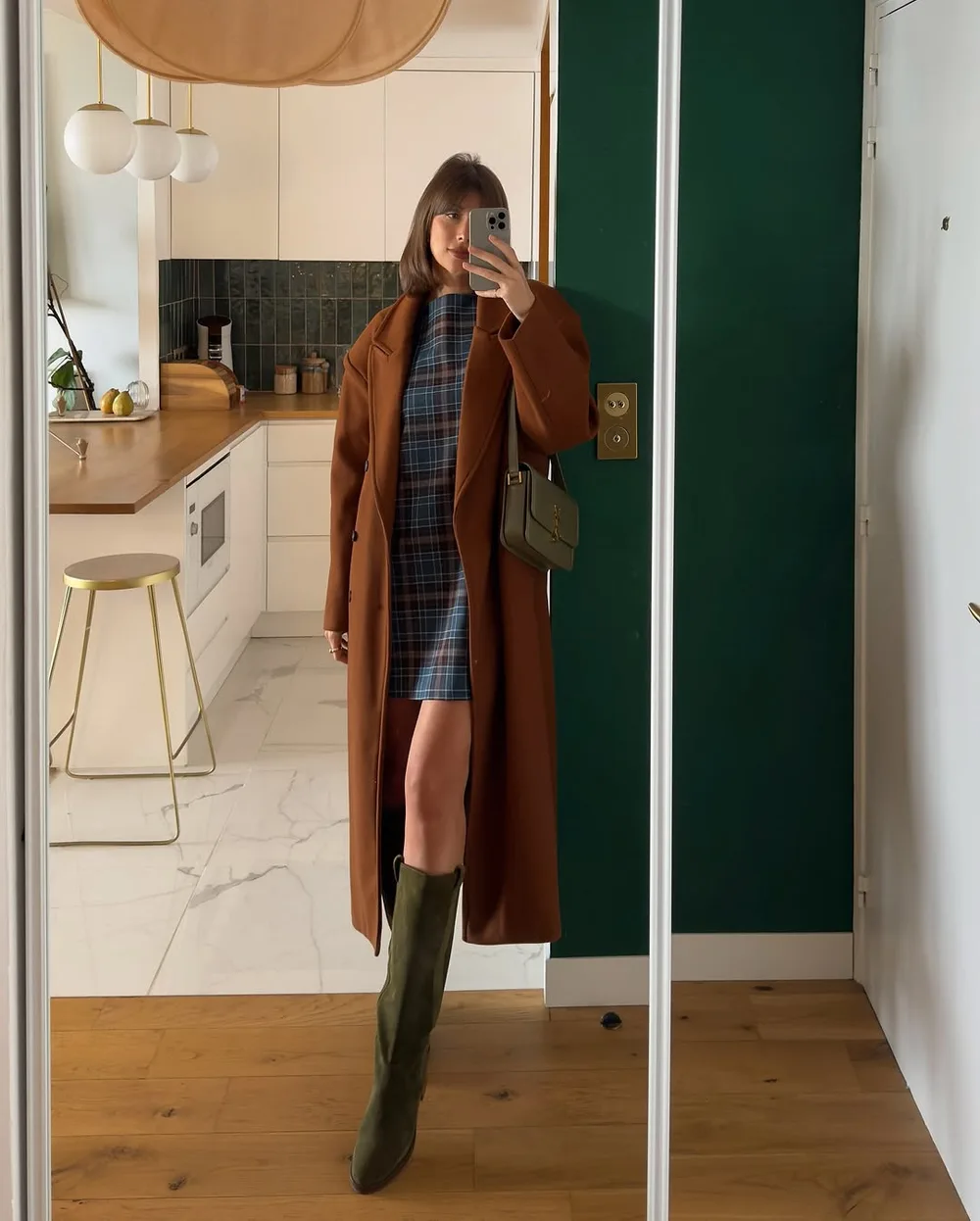 Mini robe à carreaux tartan portée avec des cuissardes daim et un long manteau